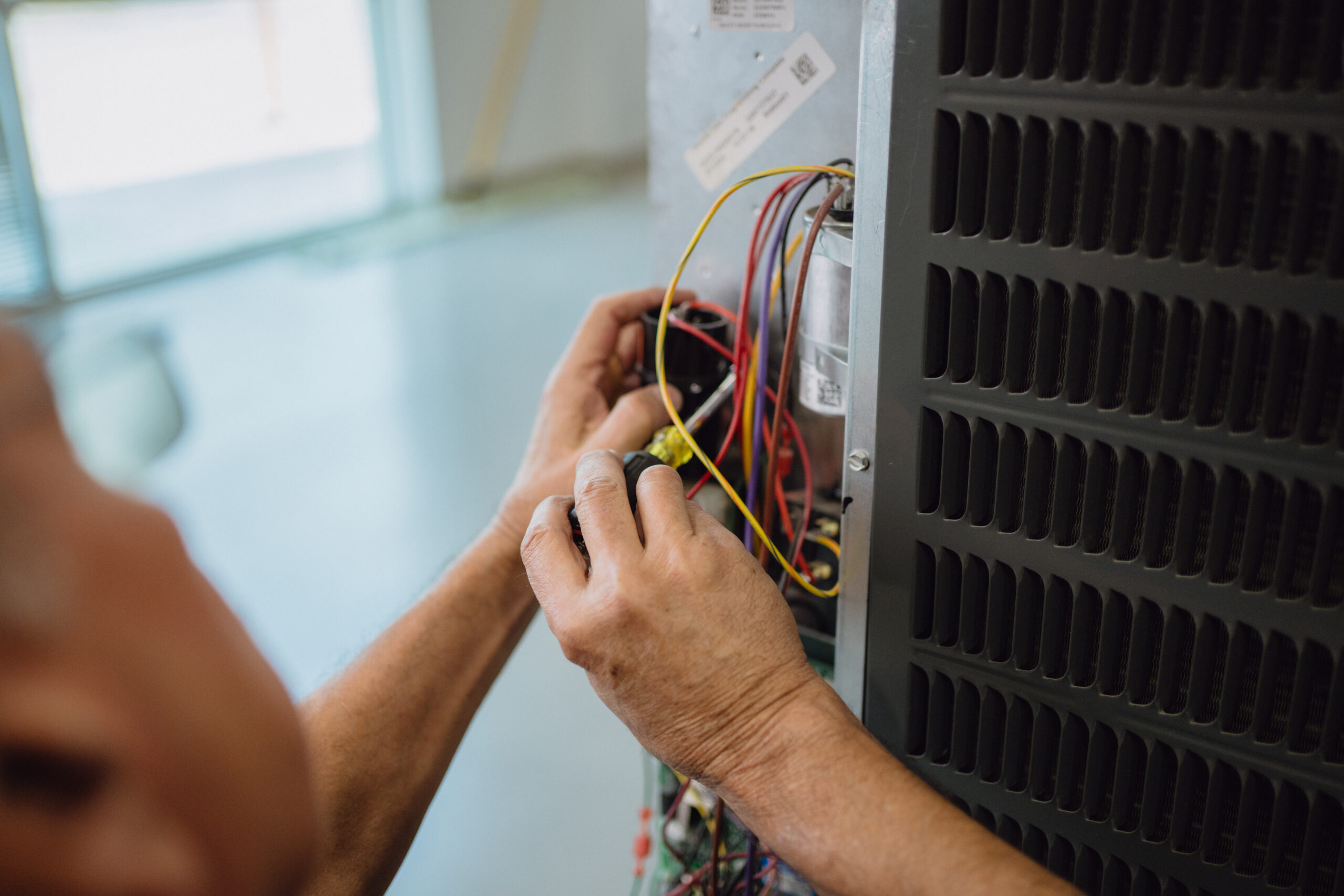 Student using screwdriver to service electrical control panel on HVAC unit