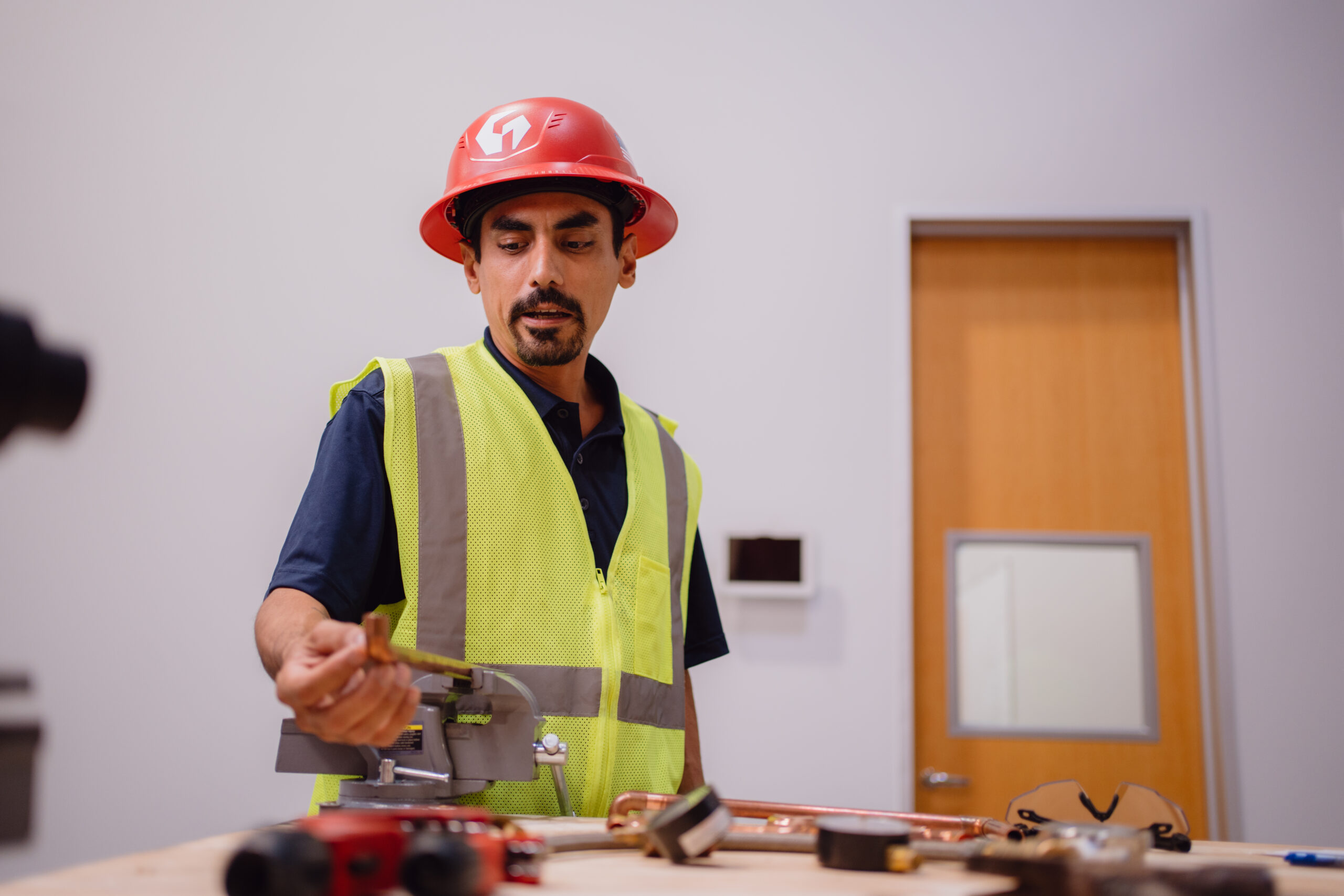Tradecraft student inspecting copper tubing secured in a bench vise during San Antonio plumbing lab