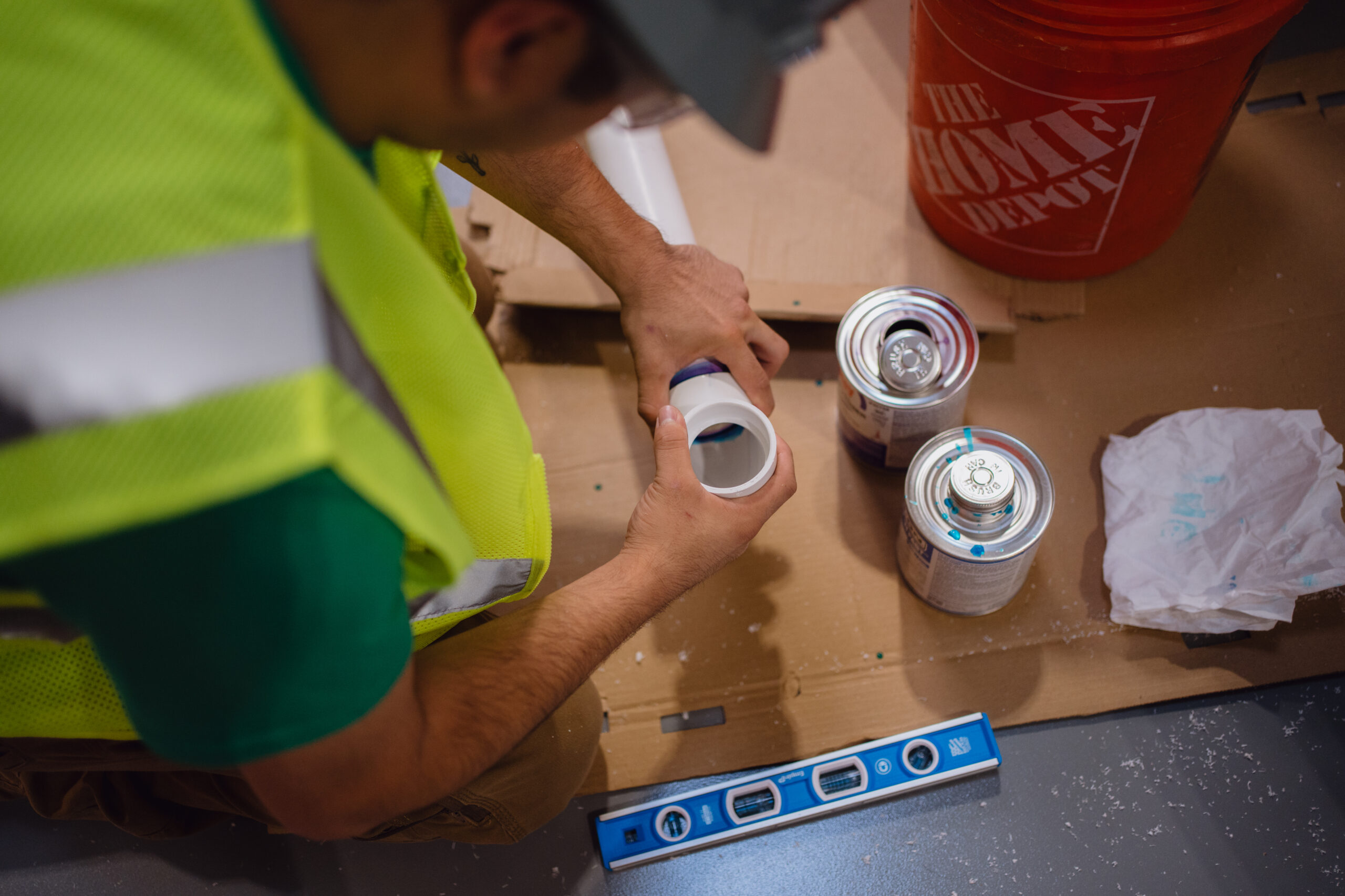 Overhead view of a Tradecraft student gluing PVC pipe joints with solvent cement in the San Antonio plumbing shop