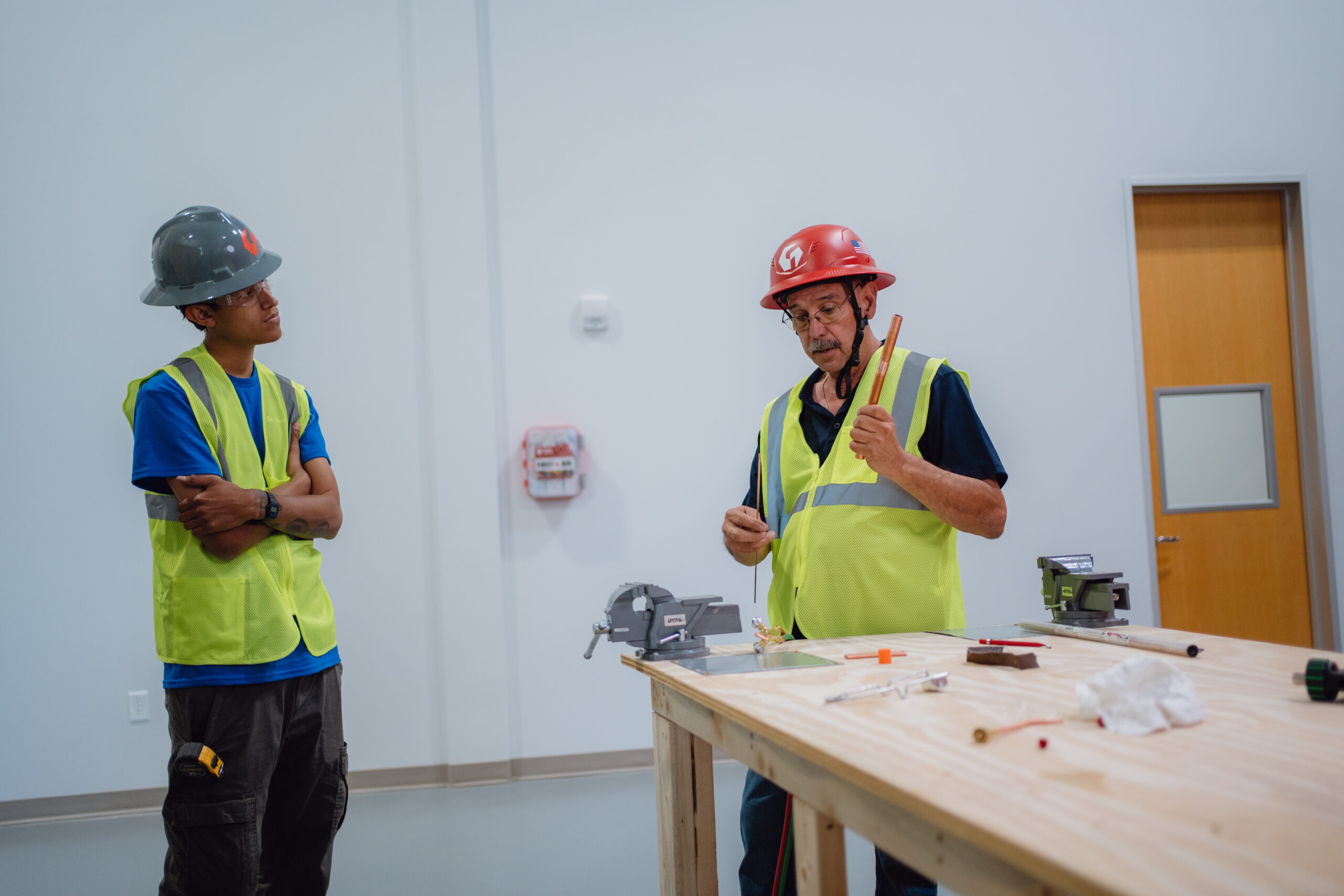 Tradecraft Schools HVAC instructor holding copper tubing while explaining brazing techniques to a student at a lab workbench in San Antonio